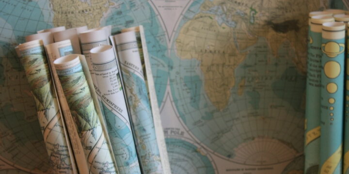 world map with rolled up maps on top of it.