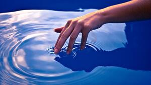 Fingers touching water, causing ripples in the water. (John Salatas / CC BY-SA)